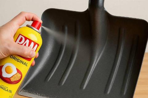 A hand spraying PAM cooking spray on a snow shovel. 
