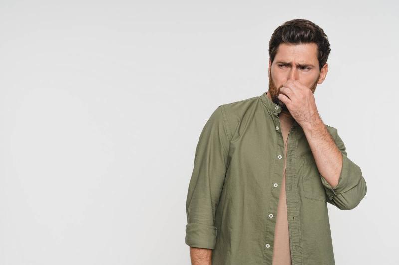 A man plugging his nose after smelling a bad smell. 