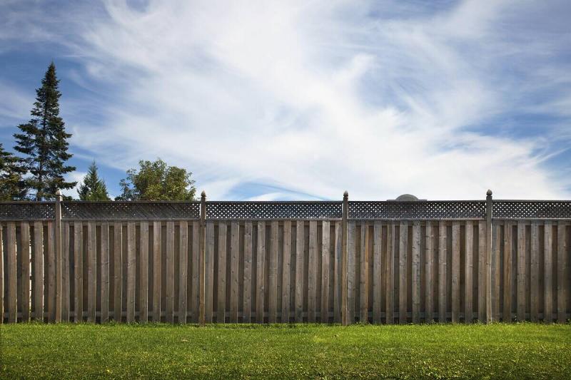 Wooden garden fence in front of a blue sky. 
