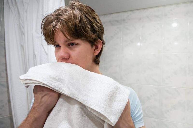 A man holding a towel up to his face. 