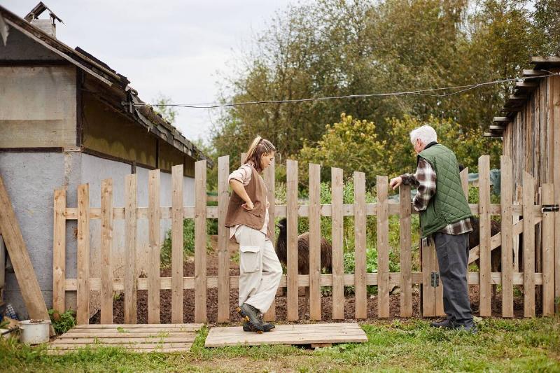 Man and woman standing by fence together. 
