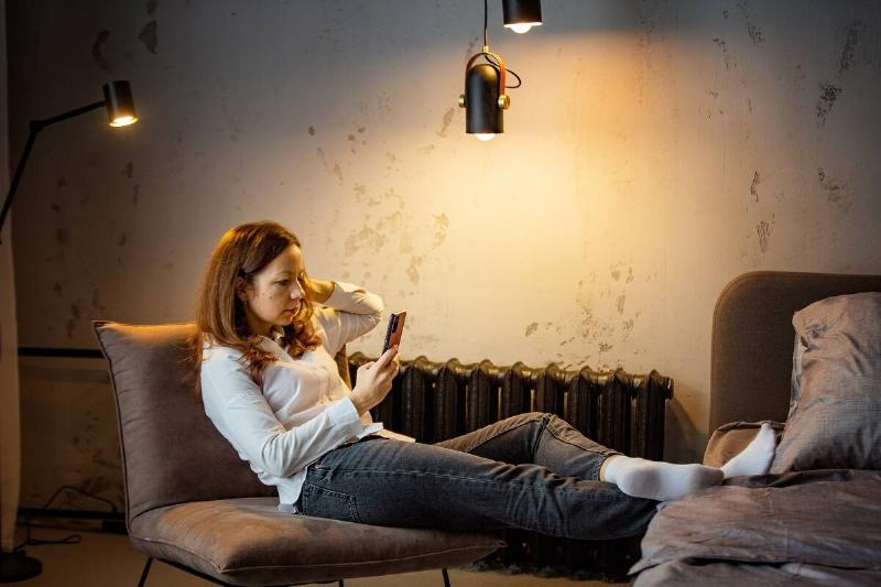 Woman looking at phone under dim, uneven lighting. 