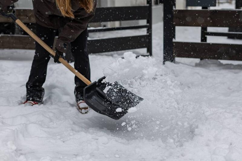 Woman shoveling snow without it sticking to the shovel. 