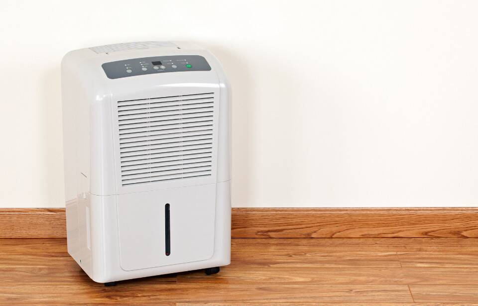 A dehumidifier on a wood floor. 