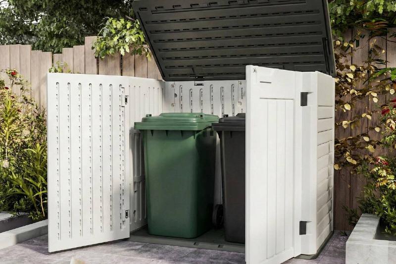 A storage shed holding garbage bins.
