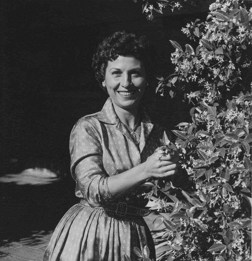 Nancy Sinatra standing next to a bush