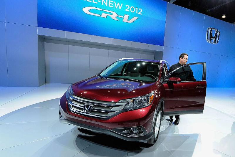 Man standing at the open door of a red 2012 Honda CR-V that's on display