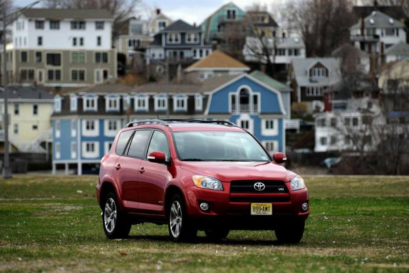 Red 2011 Toyota RAV4 parked on grass, near houses
