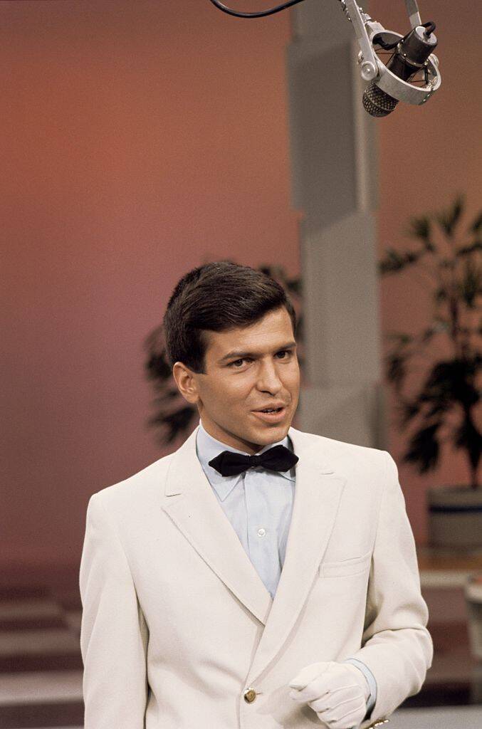 Frank Sinatra, Jr. standing in a white suit and gloves