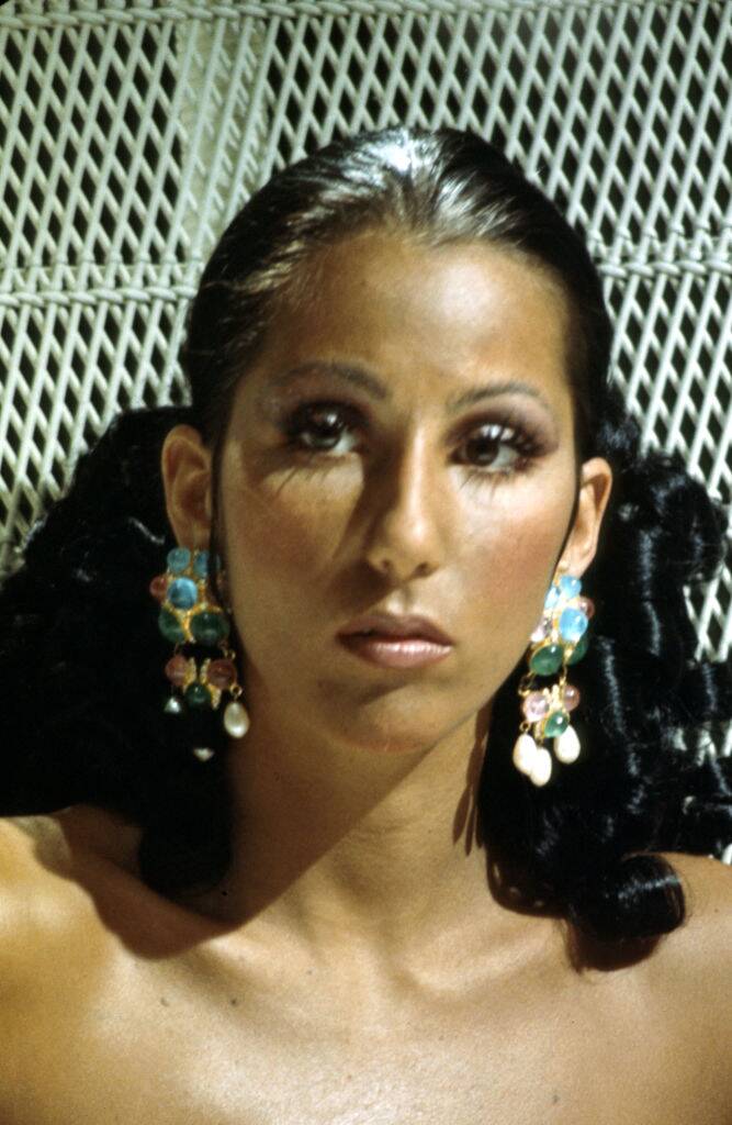 Cher sitting in a wicker chair