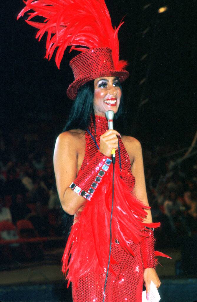 Cher standing, holding a microphone