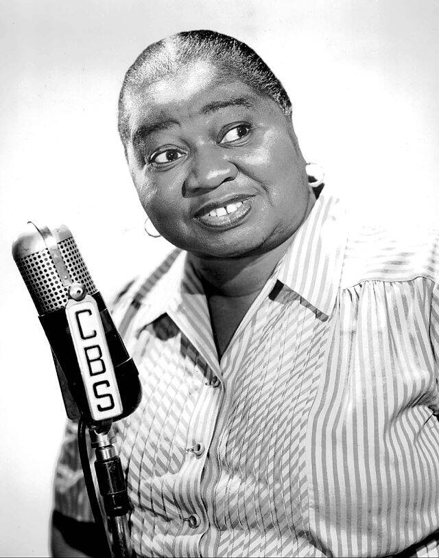 Hattie McDaniel standing next to a microphone with 