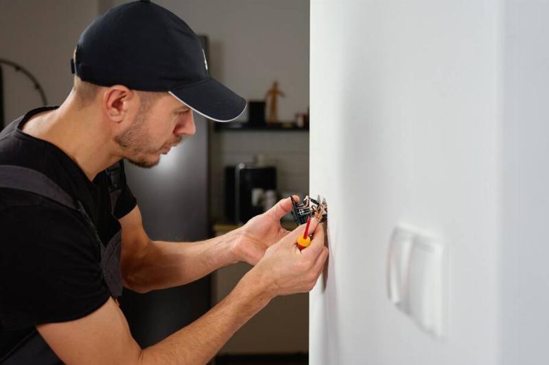 Electrician doing work on a wall outlet. 