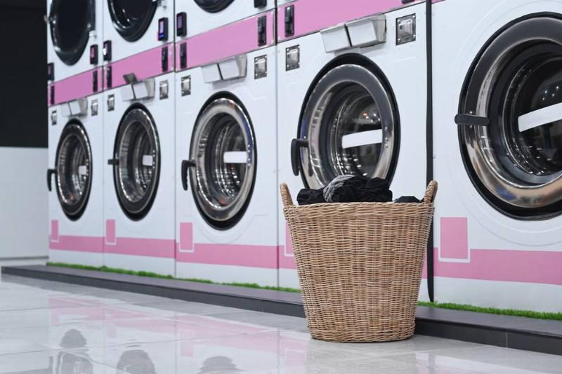 A basket of laundry near row of washing machines.