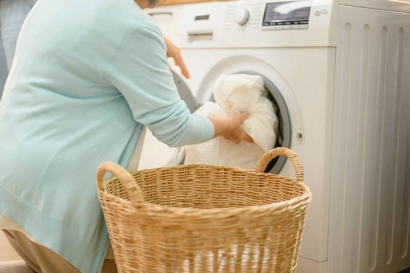 Woman putting sheets in the washing machine. 