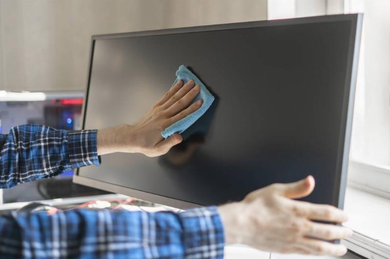 Hands wiping computer monitor. 
