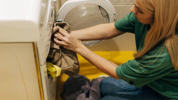 A woman loads dirty laundry into the washing machine.