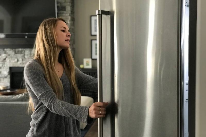 Woman looking in stainless steel fridge. 
