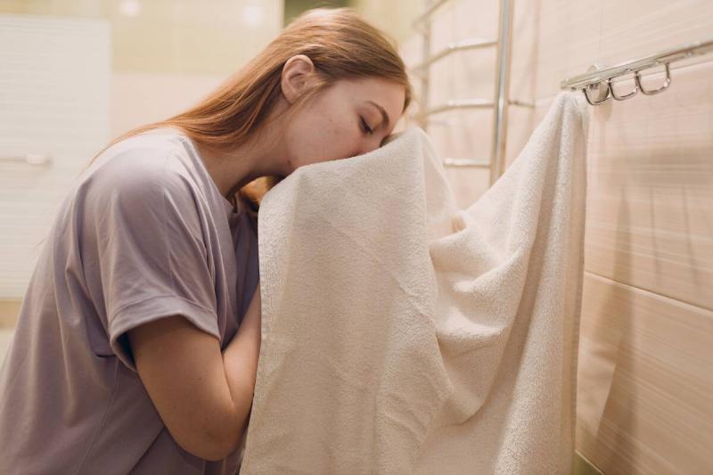 Woman wiping her face on a towel in the bathroom. 