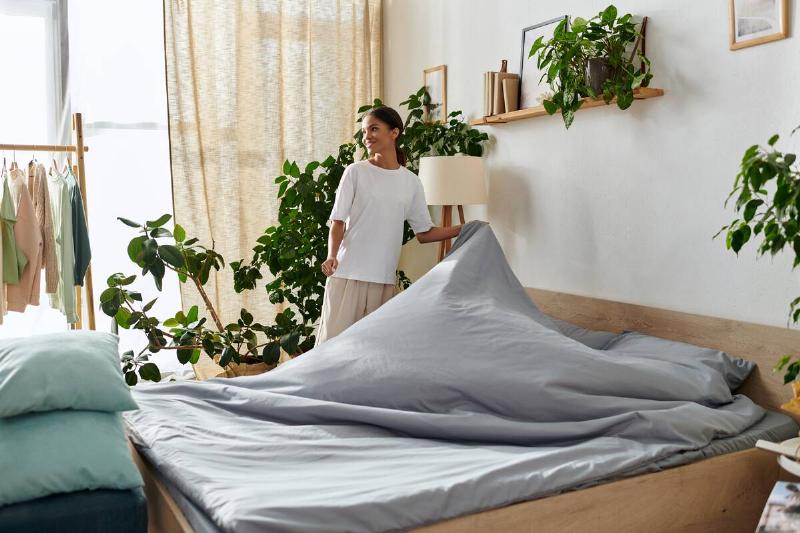 Woman taking blanket off of the bed. 