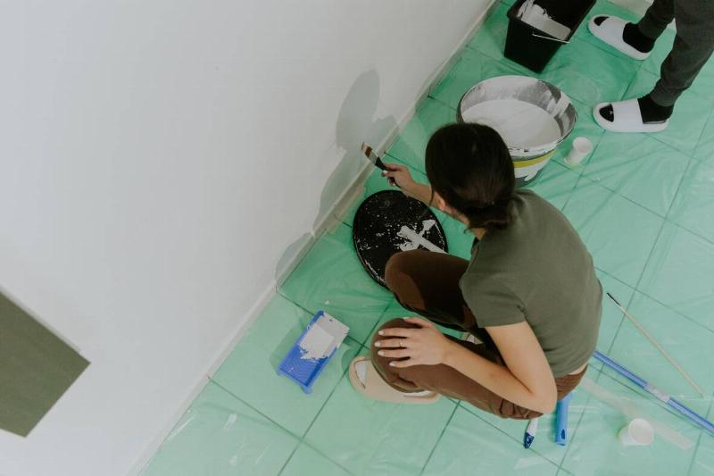 Woman painting bathroom wall. 