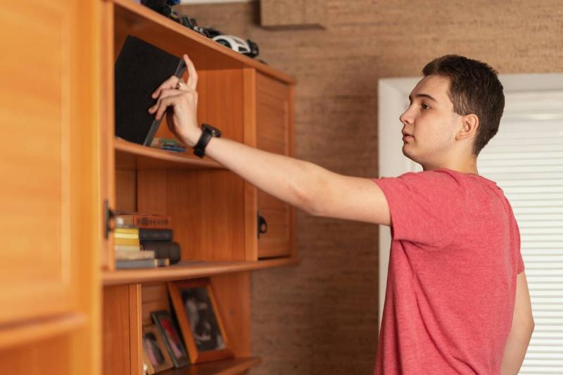A man putting things away on a shelf. 