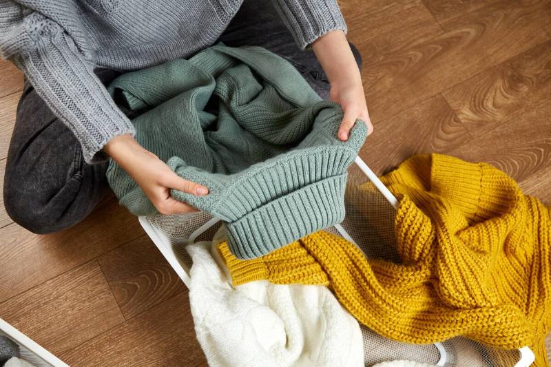Woman putting away knit sweaters. 
