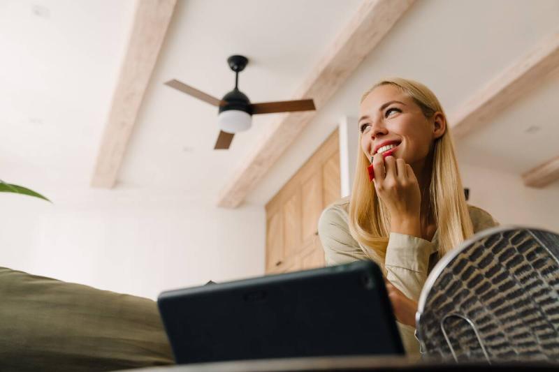 Woman sitting under ceiling fan. 