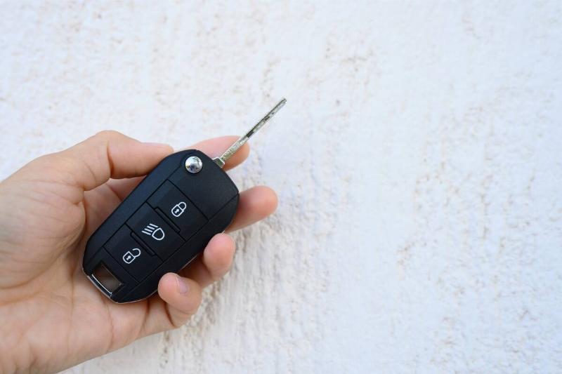 Hand holding car key fob with key extended. 