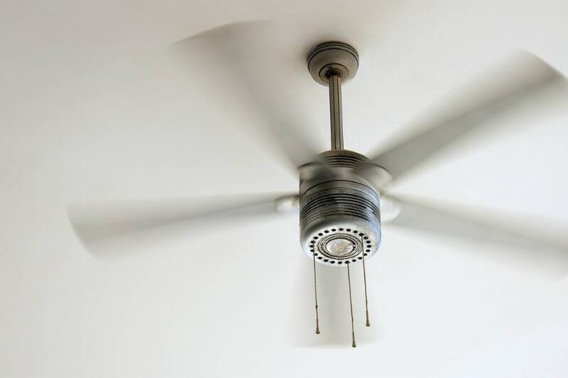 Ceiling fan is rotating at the ceiling of the room.