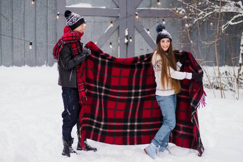 Couple bringing out blanket in snow. 