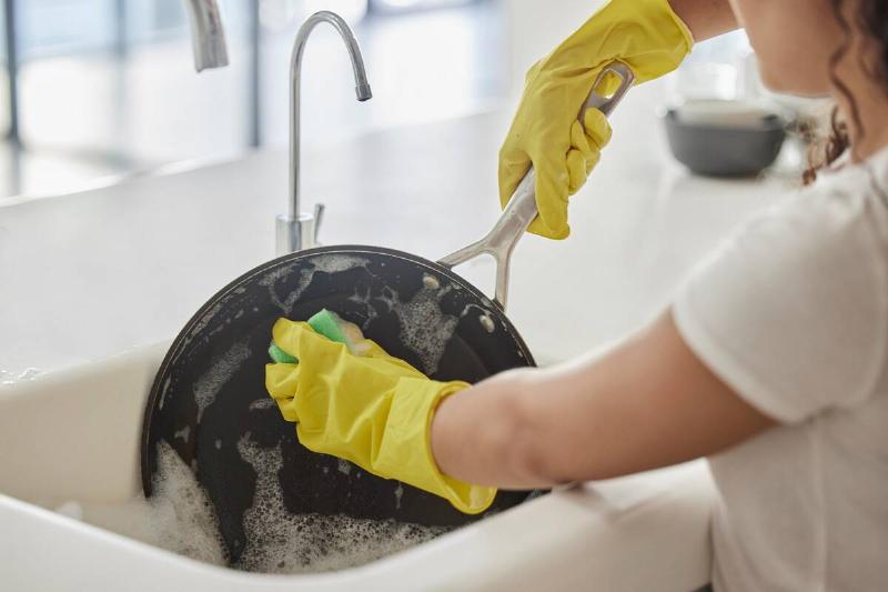 Person cleaning non-stick pan with sponge. 
