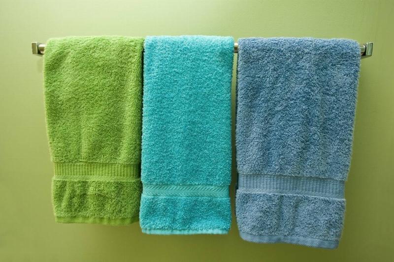 Three colorful towels with borders hanging on the hanger.