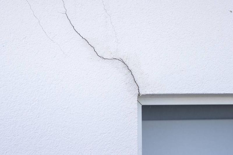 A crack in a wall coming out from a window. 