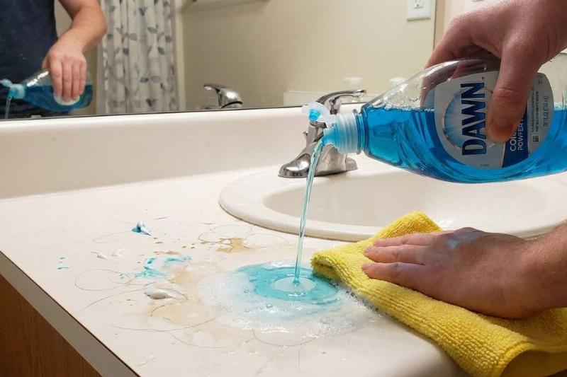 A person using the dish soap cleaner mix in the bathroom. 
