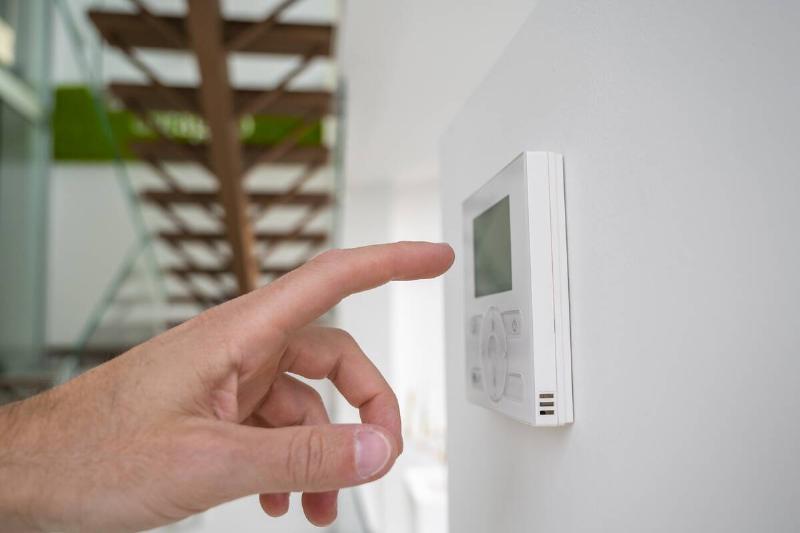 Hand pressing buttons on thermostat. 