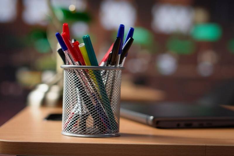 A pen organizer holding pens on a desk. 