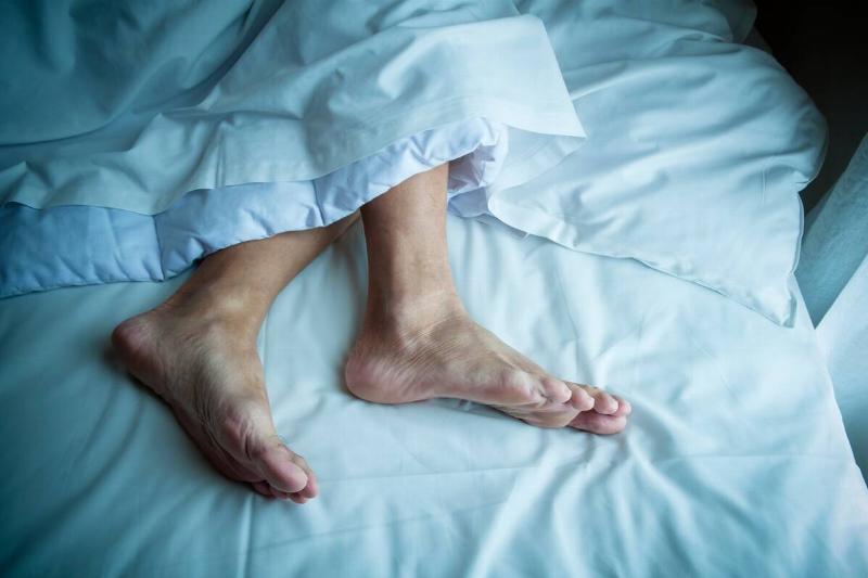 Feet of man in bed at night.