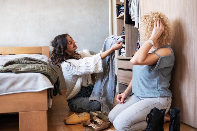 Two friends organizing a closet together. 