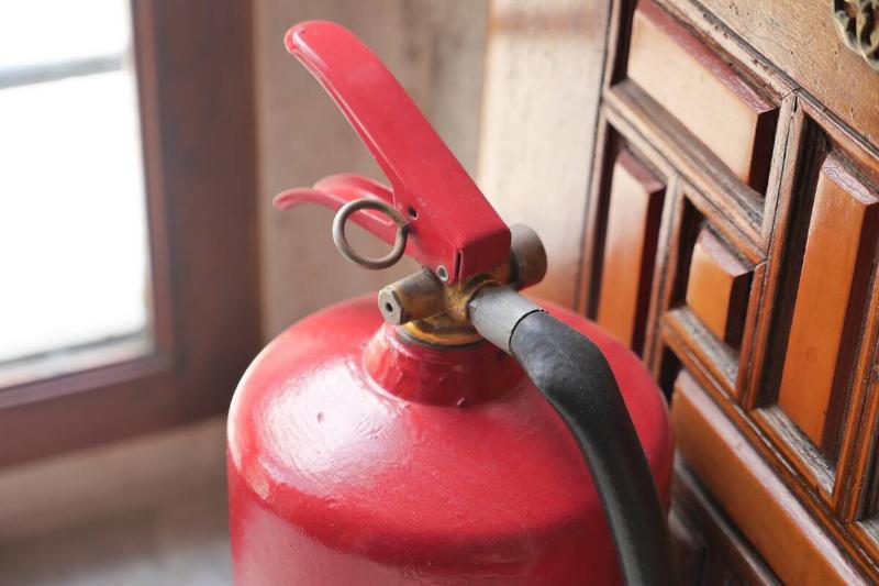 A fire extinguisher near wooden furniture. 