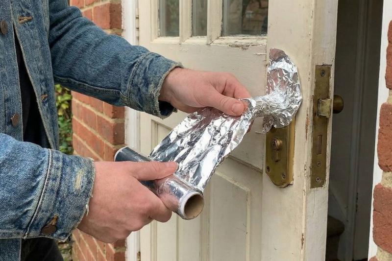 A man putting aluminum foil on their door.