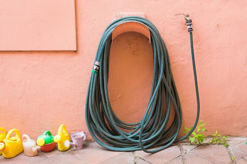 Garden hose hanging on a wall outside. 