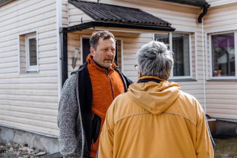 Neighbors talking in front of a house. 