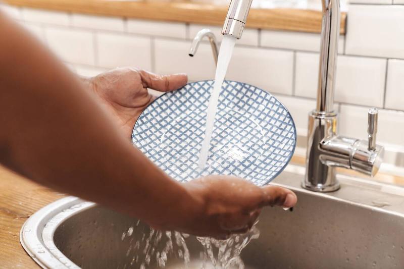 Man washing plate in sink. 