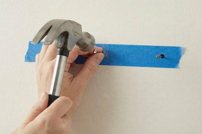 A hammer hammering nails through the marks in the tape. 