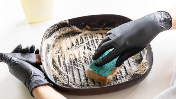 A person scrubbing their cast iron pan. 