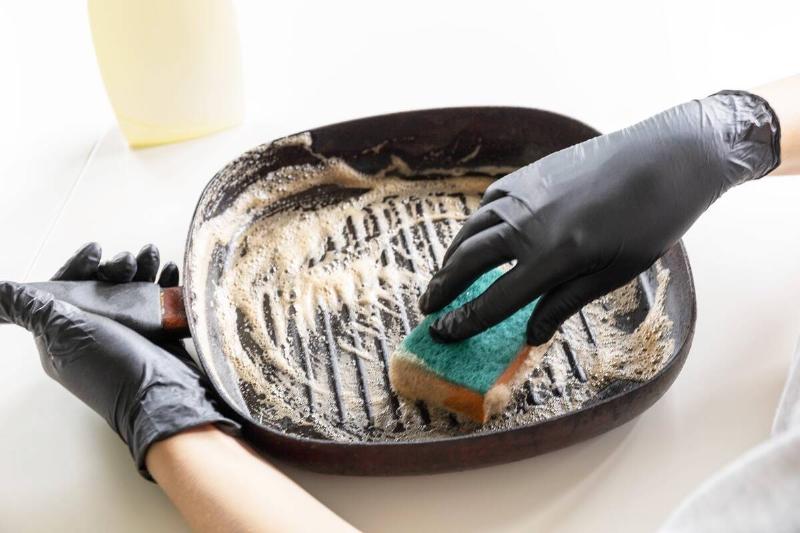 Person cleaning cast iron skillet with sponge. 