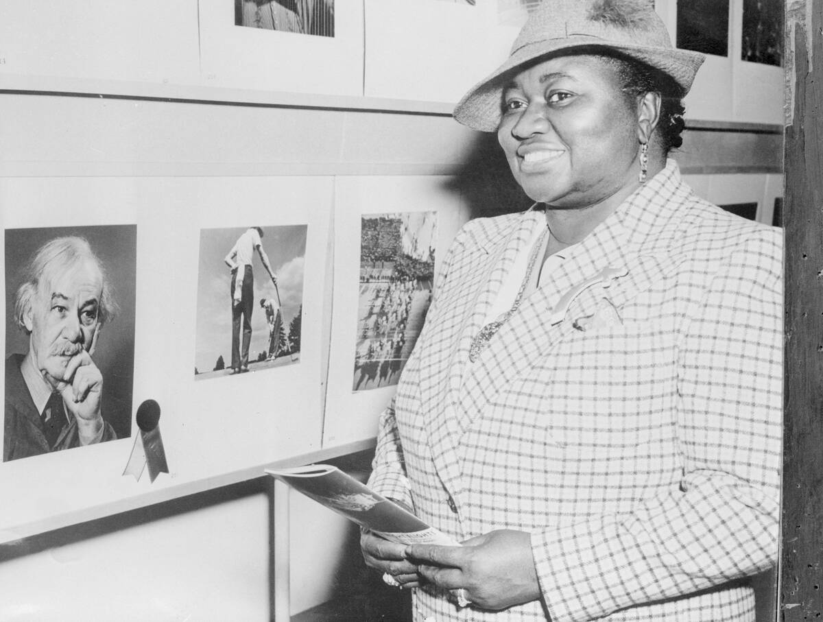 Hattie McDaniel standing next to a wall of photos