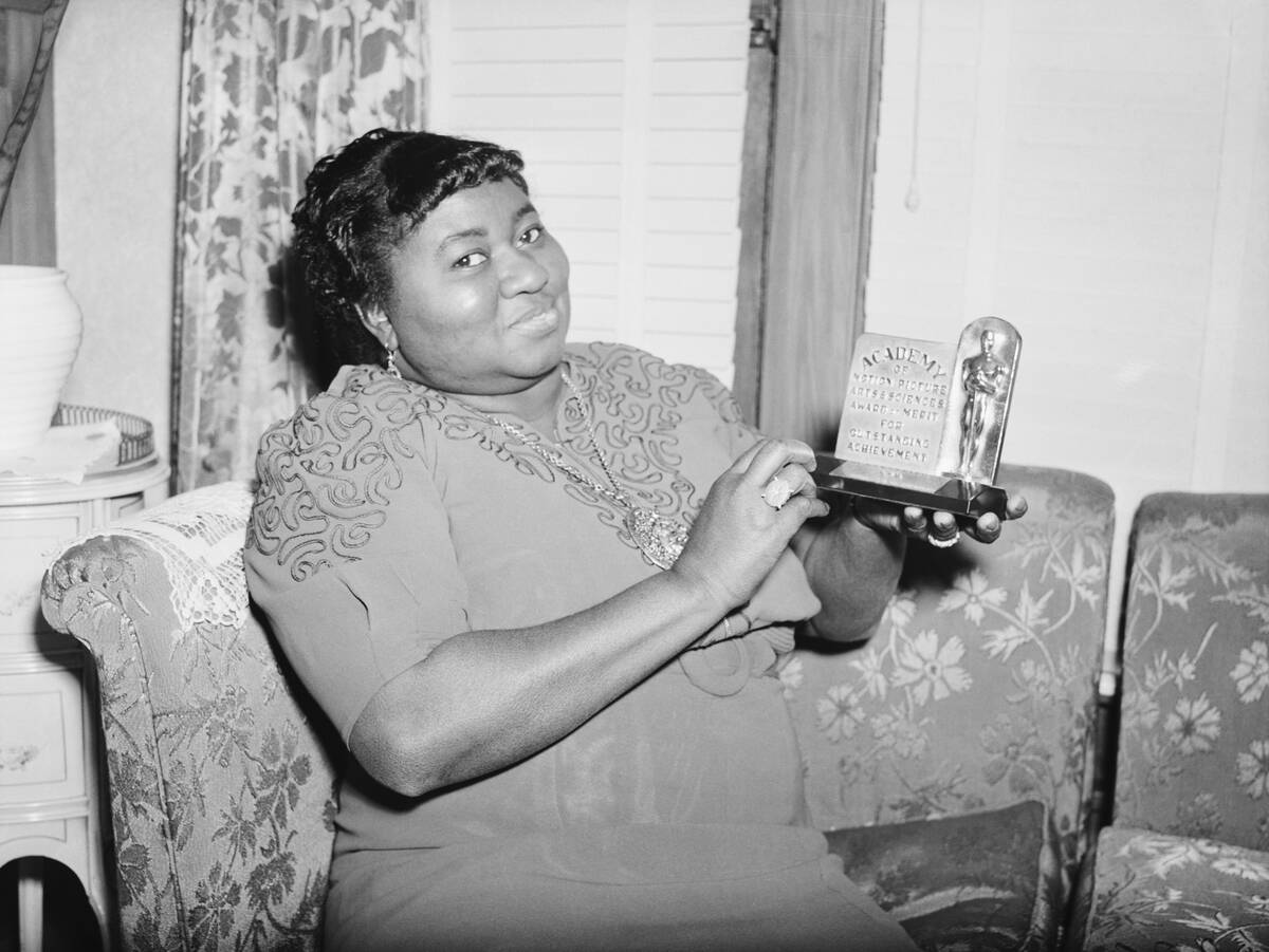 Hattie McDaniel sitting on a couch while holding her Academy Award