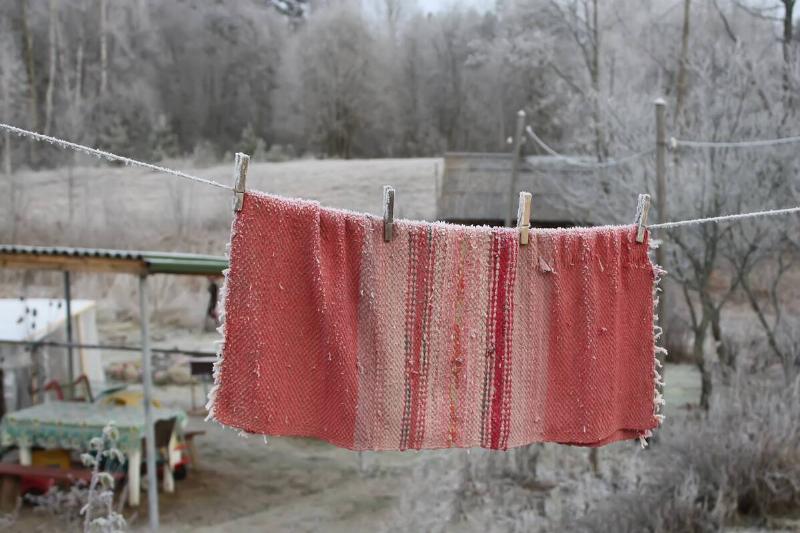 A blanket hanging on a line in winter. 